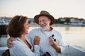 Happy senior couple hugging outdoors on pier by sea, looking at each otherand laughing. Royalty Free Stock Photo