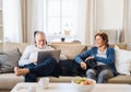 A happy senior couple sitting on a sofa indoors with a pet dog at home, using laptop. Royalty Free Stock Photo