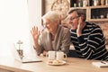 Happy senior couple looking at laptop screen in kitchen and waving Royalty Free Stock Photo