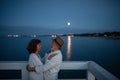 Happy senior couple in love hugging outdoors on pier by sea at moonlight, looking at each other. Royalty Free Stock Photo