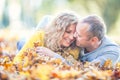 Happy mature 40s couple lying in autumn maple leaves