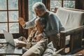 Happy senior couple man and woman doing video call with laptop at home sitting on the floor and chair together having un. Hallo Royalty Free Stock Photo