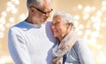 Happy senior couple over festive lights background