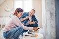 Senior couple painting walls in new home, relocation concept.