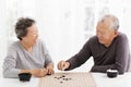 Happy senior couple playing chess in living room