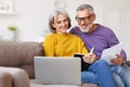 Happy senior couple reading good news in letter while paying bills online on laptop Royalty Free Stock Photo