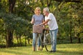 Happy senior couple relaxing at park walking with bike and talking together in morning time. old people in the autumn park .