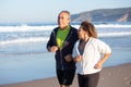 Happy senior couple running along ocean coast on summer day Royalty Free Stock Photo