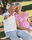 Happy Senior Couple Sitting on Bench in Sunshine Royalty Free Stock Photo
