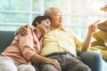 Happy senior couple sitting hugging each other on sofa at home looking out the windows peacefully Royalty Free Stock Photo