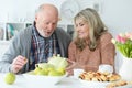 Happy senior couple sitting at kitchen table and drinking tea Royalty Free Stock Photo