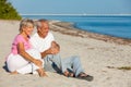 Happy Senior Couple Sitting Laughing Smiling on a Beach Royalty Free Stock Photo