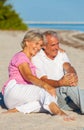 Happy Senior Couple Sitting Laughing Smiling on a Beach Royalty Free Stock Photo