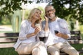 Happy senior couple sitting on park benchand listening music in earphones Royalty Free Stock Photo