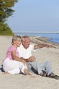 Happy Senior Couple Sitting Pointing on Beach Royalty Free Stock Photo