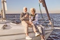 Happy senior couple sitting on the side of sail boat or yacht deck floating in sea. Man and woman drinking wine or Royalty Free Stock Photo