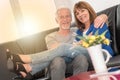 Happy senior couple sitting on sofa and embracing each other, light effect