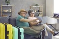 Happy senior couple sitting on sofa with laptop, planning holiday trip and booking tickets online Royalty Free Stock Photo