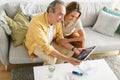 Happy senior couple smiling happily while having video call with family on digital tablet, sitting on sofa at home Royalty Free Stock Photo