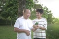 Happy senior couple smiling, talking and looking at phone in the park Royalty Free Stock Photo