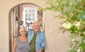 Happy senior couple smiling welcomingly at their front door Royalty Free Stock Photo
