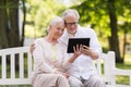 Happy senior couple with tablet pc at summer park