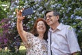 Happy senior couple taking a self portrait in a garden, surrounded by flowers Royalty Free Stock Photo