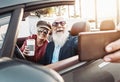 Happy senior couple taking selfie on new modern convertible car - Mature people having fun together making self photos