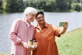 Happy senior couple taking selfie photo outdoors together enjoying walk in park Royalty Free Stock Photo