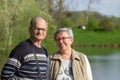 Happy senior couple tourists walking in spring city park near the lake. Smiling elderly married in glasses together. Royalty Free Stock Photo