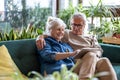 Happy senior couple using digital tablet while sitting on sofa Royalty Free Stock Photo