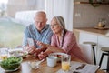 Happy senior couple using smartphone during eating dinner together at home. Royalty Free Stock Photo