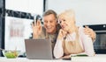 Happy Senior Couple Video Calling Using Laptop Sitting In Kitchen Royalty Free Stock Photo