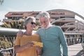 Happy senior couple walking on a bridge in the city. Looking at the same mobile phone and smiling. Elderly modern and