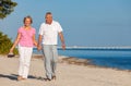 Happy Senior Couple Walking Holding Hands on a Beach Royalty Free Stock Photo