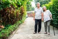 Happy senior couple walking together in the garden. Old elderly using a walking stick to help walk balance. Concept of  Love and Royalty Free Stock Photo