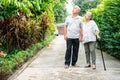 Happy senior couple walking together in the garden. Old elderly using a walking stick to help walk balance. Concept of  Love and Royalty Free Stock Photo