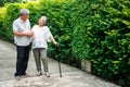 Happy senior couple walking together in the garden. Old elderly using a walking stick to help walk balance. Concept of  Love and Royalty Free Stock Photo