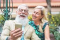 Happy senior couple watching on mobile smart phone and laughing together - Mature fashion people having fun with new technology Royalty Free Stock Photo