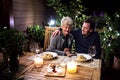 Senior couple in wheelchair having dinner in the evening on terrace, having good time. Royalty Free Stock Photo