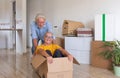 Happy senior couple white haired having fun during relocation, excited for the new beginning.  Moving boxes on the floor, empty Royalty Free Stock Photo