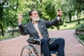 Happy senior disabled or handicapped bearded man sitting on a wheelchair in park, using his smartphone for photographing Royalty Free Stock Photo