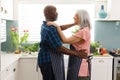 Happy senior diverse couple wearing aprons and dancing in kitchen Royalty Free Stock Photo