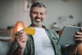 Happy senior european man with beard shopping online, holding tablet and credit card, enjoy huge sale Royalty Free Stock Photo