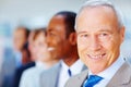 Happy senior executive with colleagues in background. Focus on senior Business man with team behind him looking to side. Royalty Free Stock Photo