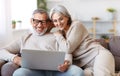 Happy senior family couple watching comedy or funny video on laptop while spending free time at home Royalty Free Stock Photo