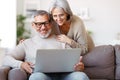 Happy senior family couple watching comedy or funny video on laptop while spending free time at home Royalty Free Stock Photo