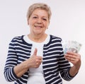 Happy senior female holding polish currency money and showing thumbs up, financial security in old age