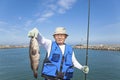 Happy senior fisherman showing large grouper