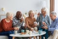 Happy senior friends playing cards while chilling together at home Royalty Free Stock Photo